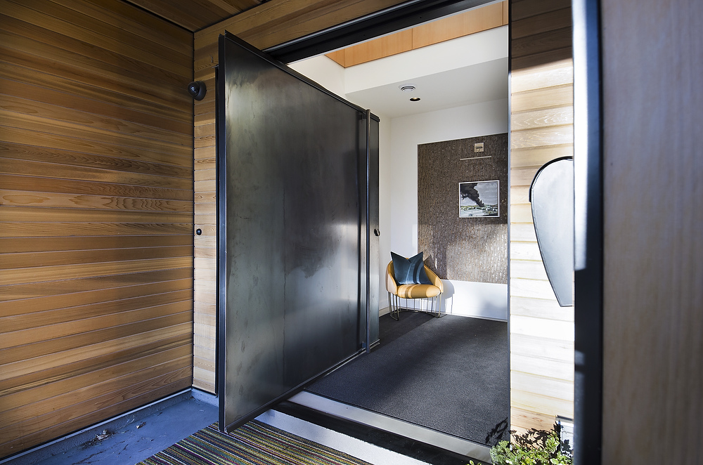 Image of wide metal swing door from the exterior of a luxury home